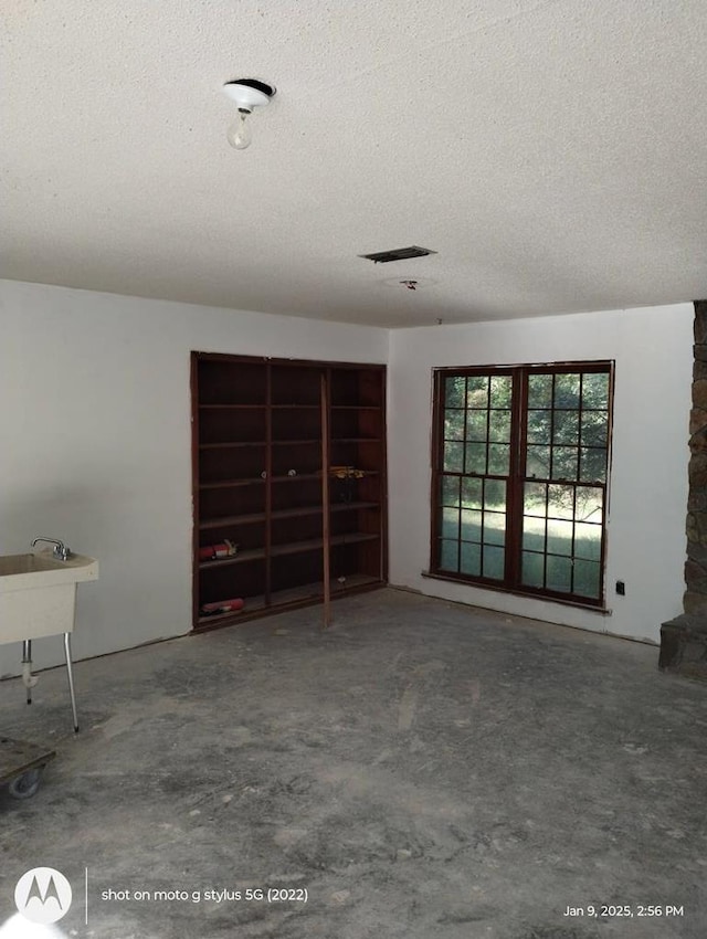 interior space with a textured ceiling, visible vents, and unfinished concrete flooring