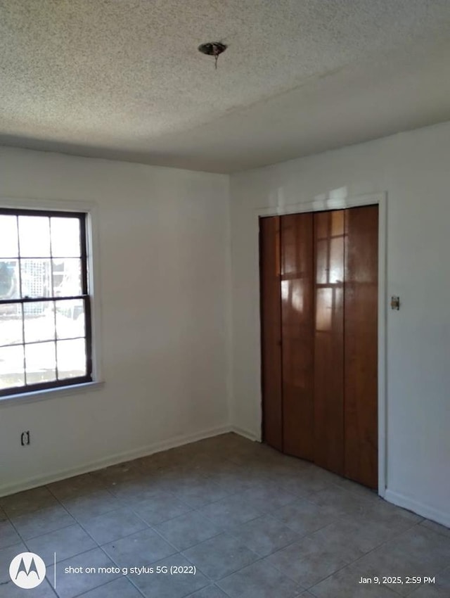 unfurnished bedroom featuring tile patterned flooring, baseboards, and a textured ceiling