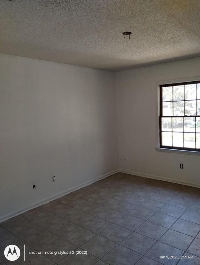 spare room with a textured ceiling and baseboards