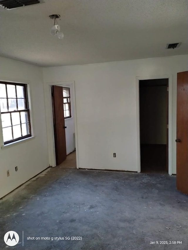 spare room featuring visible vents and unfinished concrete floors