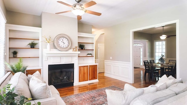 200 Sawgrass Ln, Thomasville, GA 31757 - living room featuring a ceiling fan, light wood finished floors, built in features, wainscoting, and a glass covered fireplace