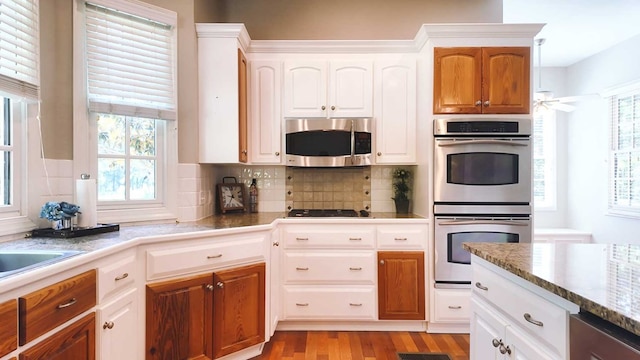 200 Sawgrass Ln, Thomasville, GA 31757 - kitchen with stainless steel appliances, light wood-style floors, decorative backsplash, and white cabinets