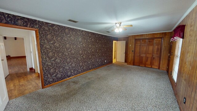 unfurnished bedroom featuring ornamental molding, a closet, ceiling fan, and carpet flooring