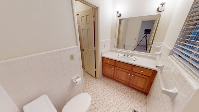 bathroom featuring vanity, toilet, and tile walls