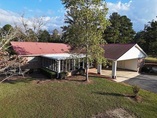 view of front of house with a carport, a sunroom, and a front lawn