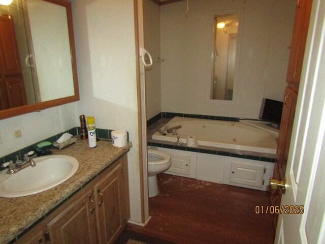 bathroom with tiled tub, vanity, and toilet