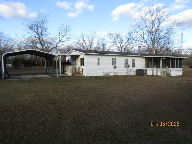 view of front of property featuring a front yard, central AC, a sunroom, and a carport