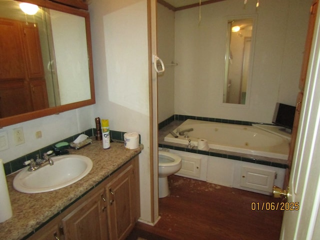 bathroom with a relaxing tiled tub, vanity, and toilet