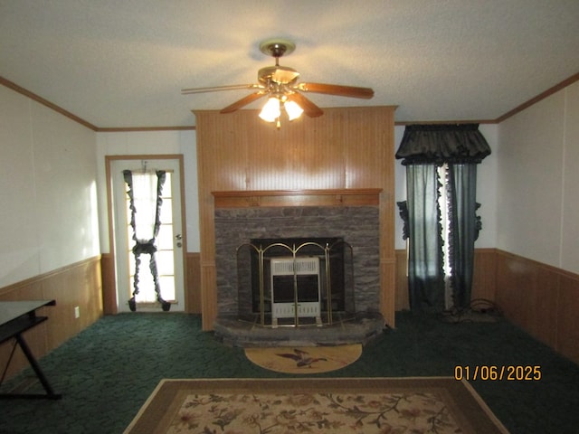 carpeted living room featuring crown molding, a fireplace, wooden walls, and ceiling fan