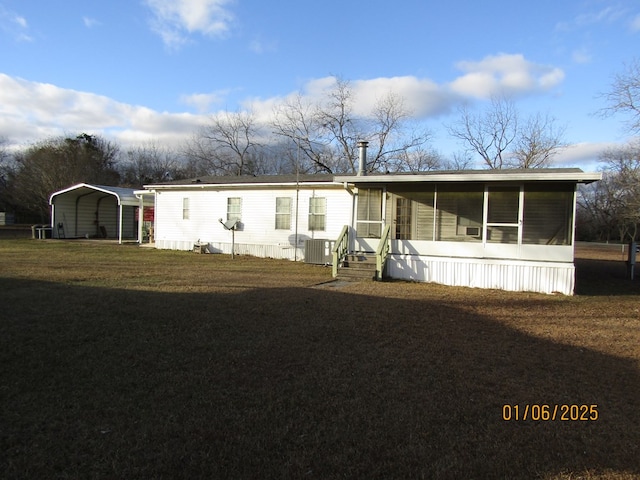 view of front facade featuring a carport, a sunroom, a front yard, and central air condition unit