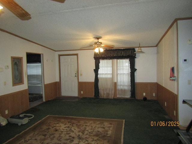 interior space featuring lofted ceiling, ornamental molding, ceiling fan, and wood walls