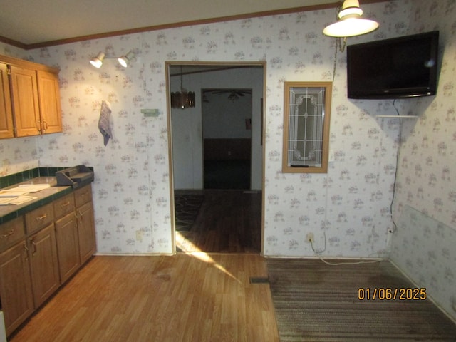 kitchen with ornamental molding, tile countertops, and light hardwood / wood-style floors