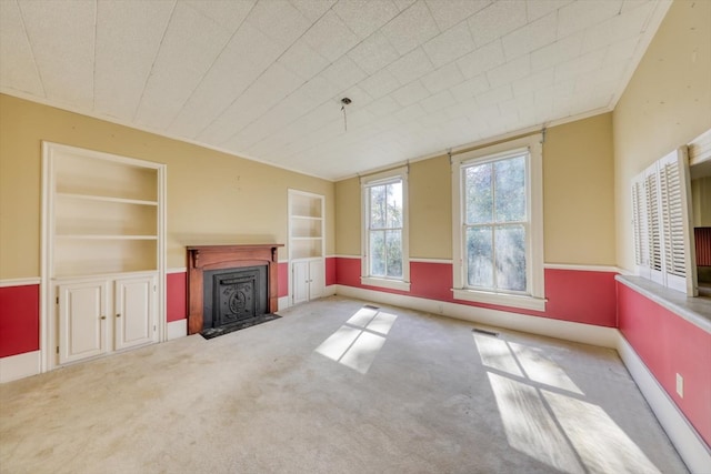 unfurnished living room with built in features and carpet