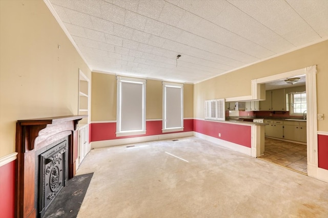 unfurnished living room with light carpet, sink, and crown molding