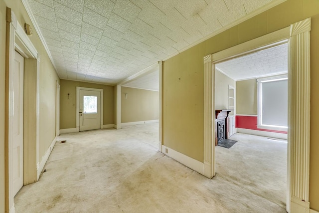 hallway with ornamental molding and carpet