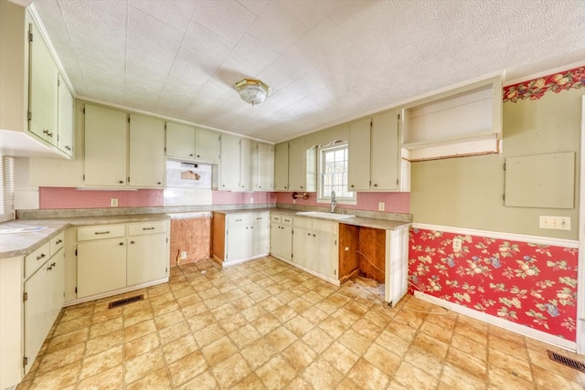 kitchen with sink, cream cabinets, and a textured ceiling