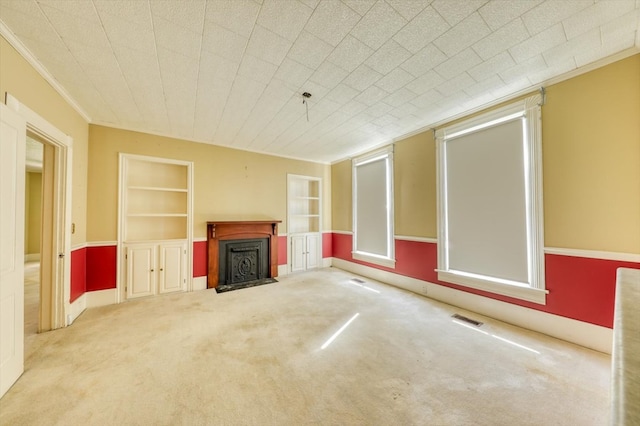 unfurnished living room featuring ornamental molding, light carpet, and built in features