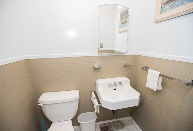 bathroom with tile walls, sink, and toilet