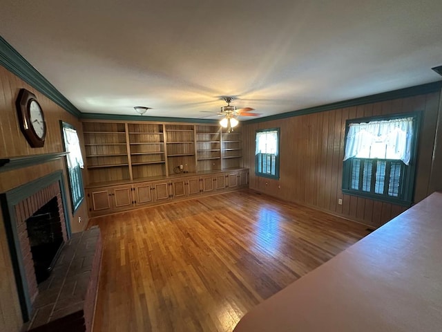 unfurnished living room featuring ornamental molding, a brick fireplace, and light hardwood / wood-style floors