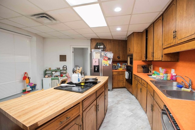6715 Stewart Rd, Ochlocknee, GA 31773 - kitchen featuring a sink, black appliances, brown cabinetry, a drop ceiling, and butcher block counters