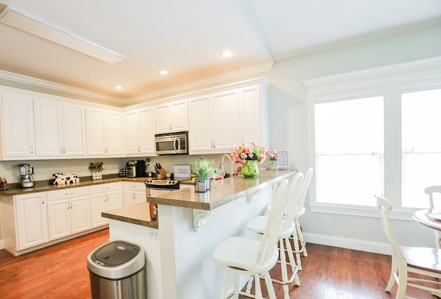 351 Virginia Cir, Cairo, GA 39828 - kitchen featuring stainless steel appliances, a kitchen bar, white cabinets, a peninsula, and light wood finished floors