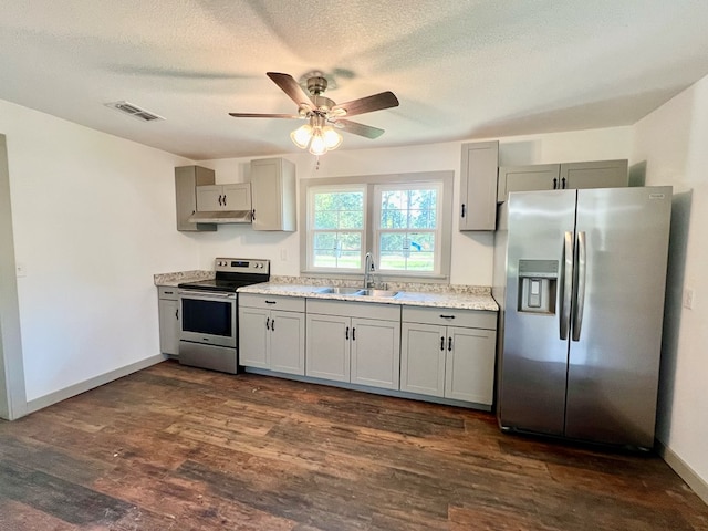 kitchen with sink, a textured ceiling, appliances with stainless steel finishes, dark hardwood / wood-style floors, and gray cabinets