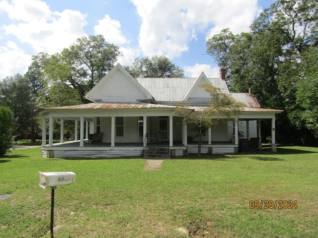 rear view of property featuring a yard and covered porch