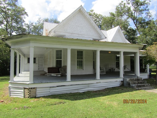 back of house with covered porch and a lawn