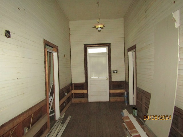 hallway with a high ceiling, wood-type flooring, and wood walls