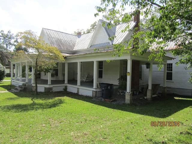 rear view of house featuring covered porch and a lawn