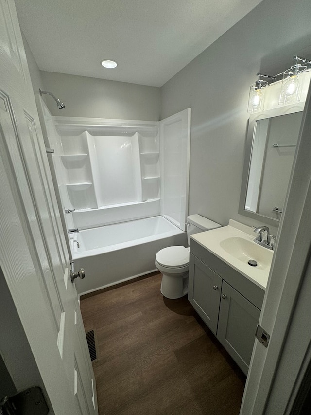 full bathroom with hardwood / wood-style flooring, shower / bath combination, vanity, and toilet