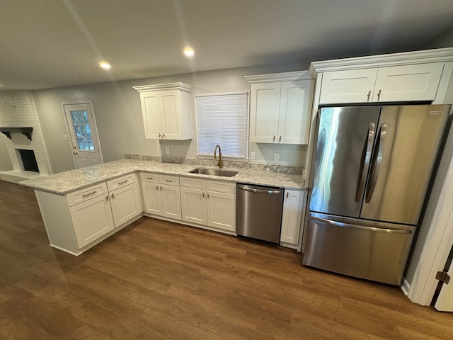 kitchen featuring sink, dark wood-type flooring, appliances with stainless steel finishes, white cabinets, and kitchen peninsula