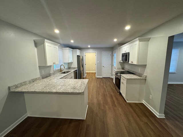 kitchen with sink, white cabinetry, stainless steel appliances, dark hardwood / wood-style floors, and kitchen peninsula