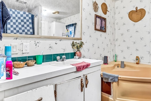 bathroom with vanity, a textured ceiling, and a tub