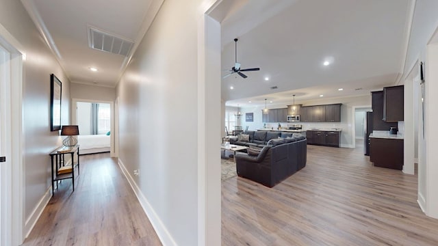 hallway featuring light wood-type flooring and ornamental molding