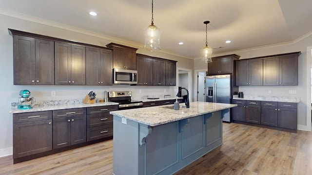 kitchen featuring a center island with sink, sink, pendant lighting, stainless steel appliances, and light stone countertops