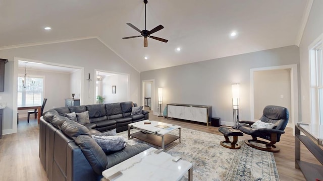 living room featuring ceiling fan with notable chandelier, light wood-type flooring, lofted ceiling, and crown molding