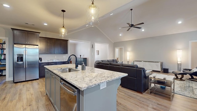 kitchen featuring appliances with stainless steel finishes, a center island with sink, dark brown cabinets, pendant lighting, and sink