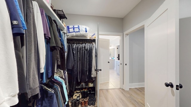 walk in closet with light hardwood / wood-style flooring