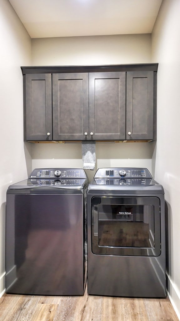 washroom featuring light hardwood / wood-style flooring, washer and clothes dryer, and cabinets