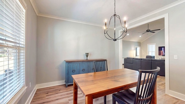 dining room featuring ceiling fan with notable chandelier, ornamental molding, light wood-type flooring, and vaulted ceiling