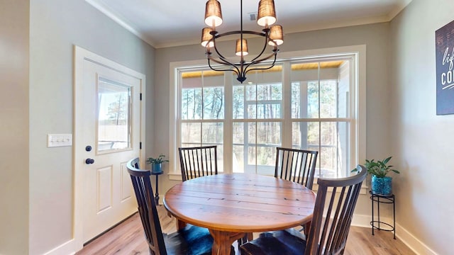 dining room featuring ornamental molding, an inviting chandelier, a healthy amount of sunlight, and light hardwood / wood-style flooring