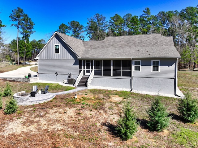 rear view of house featuring central AC, a sunroom, and a fire pit