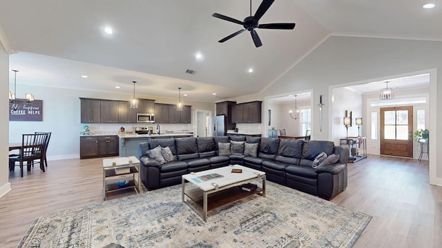 living room featuring sink, ornamental molding, high vaulted ceiling, and light hardwood / wood-style flooring