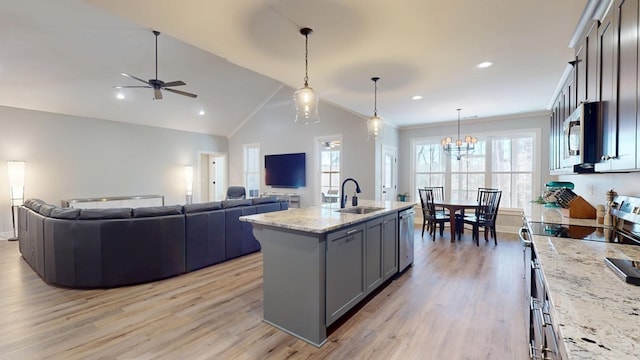 kitchen with sink, stainless steel appliances, hanging light fixtures, an island with sink, and light stone countertops