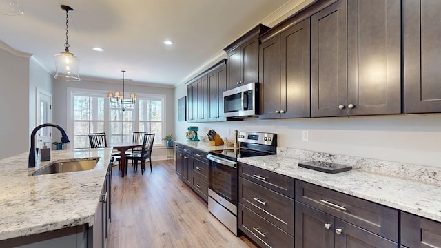 kitchen featuring pendant lighting, stainless steel appliances, light stone countertops, and sink