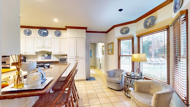 kitchen with a breakfast bar area, white cabinetry, crown molding, and light tile patterned flooring