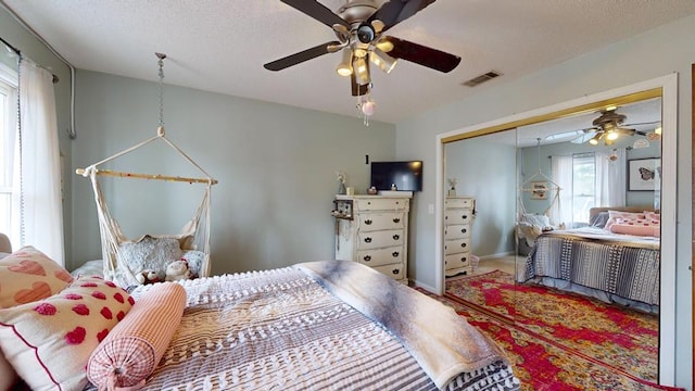 bedroom with visible vents, a ceiling fan, carpet, a textured ceiling, and a closet