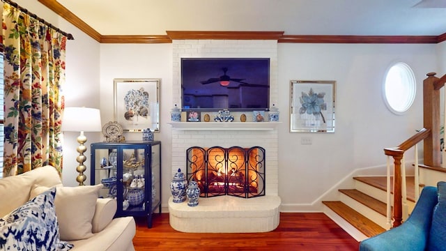 living room featuring a brick fireplace, stairs, ornamental molding, and wood finished floors