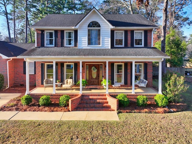 view of front of property featuring a porch, brick siding, and a shingled roof